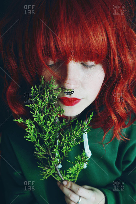 Young red haired woman holding fir twigs