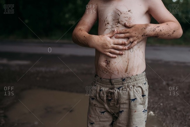 Boy spreading mud over his chest