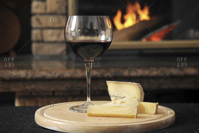 Close Up Of Wine With Cheese Slices Served On Wooden Tray Against
