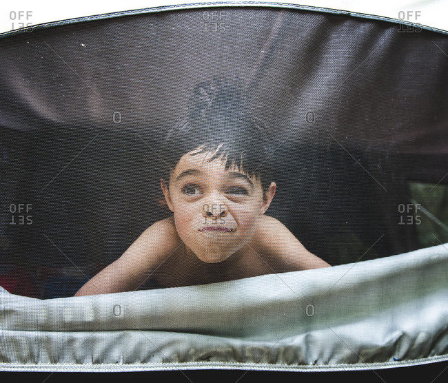 Boy making face while looking through tent