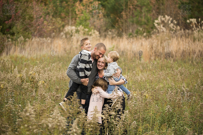 Happy parents embracing children while standing amidst plants against trees in forest