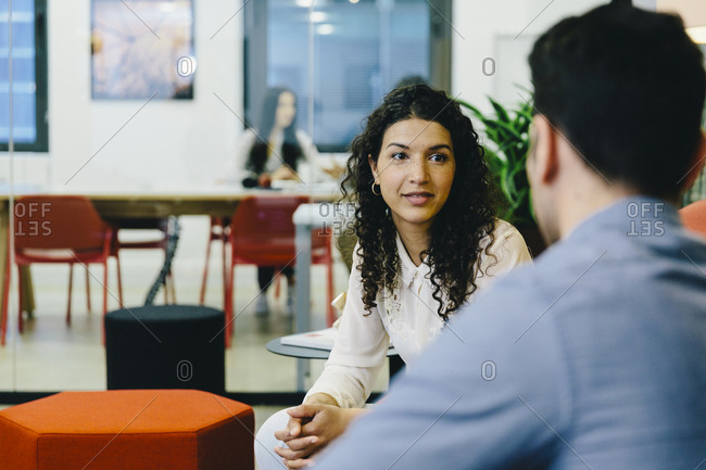 Businessman discussing with female colleague while sitting in creative office