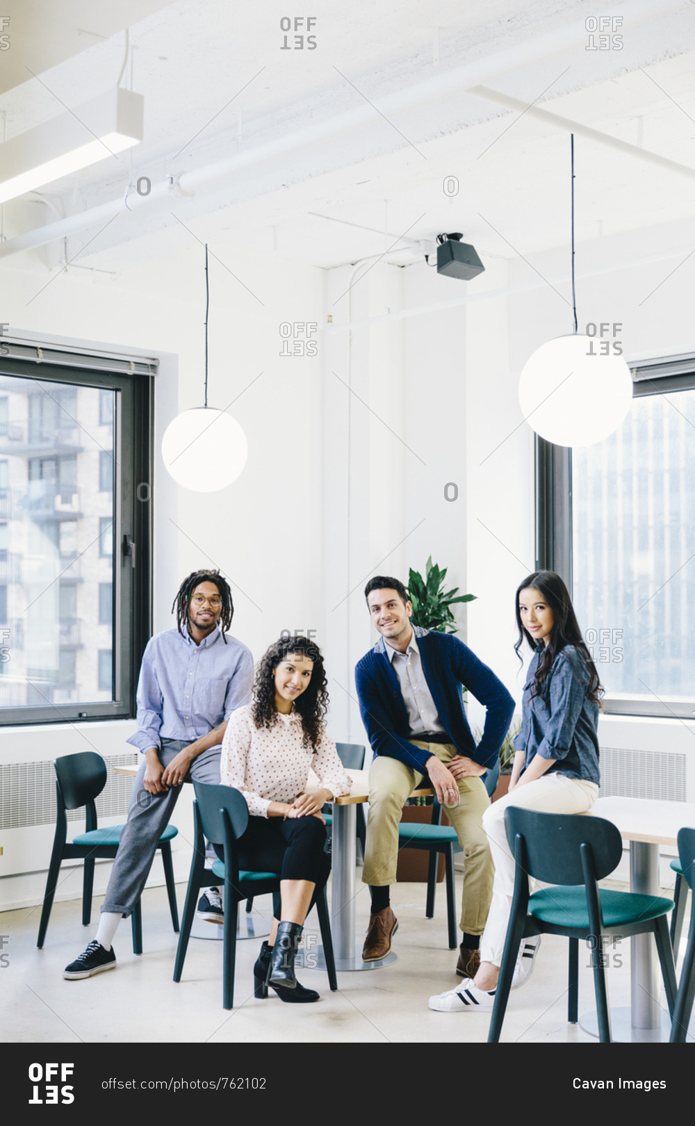 Portrait of smiling business people sitting in creative office stock