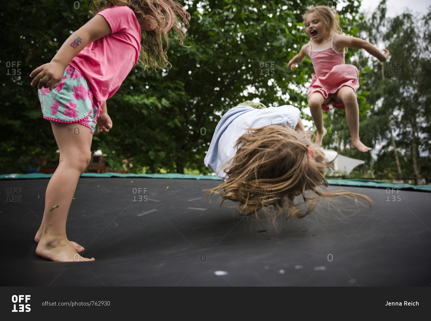 Energetic children jumping on trampoline together stock photo OFFSET