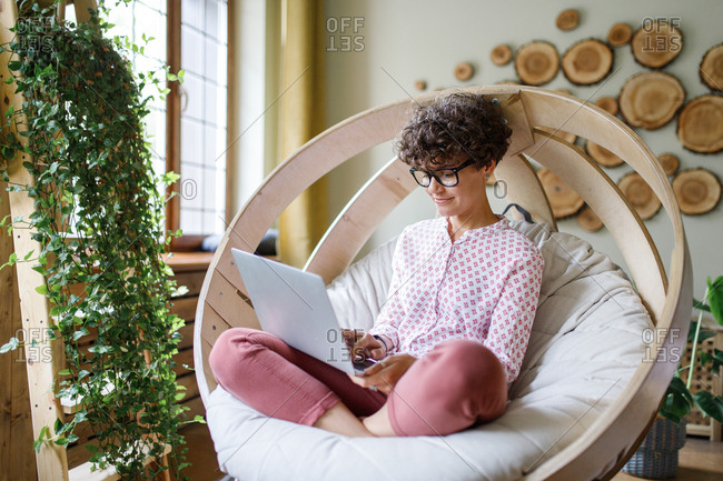 Woman sitting in round chair using laptop stock photo OFFSET