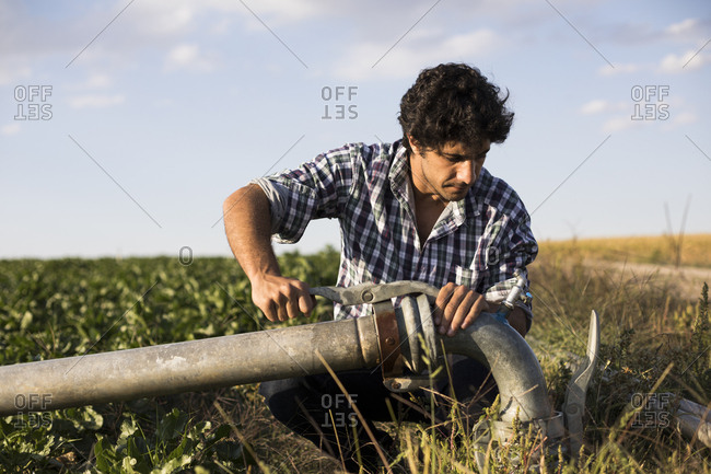 Man in casual outfit examining a watering pipe in a farm in Salamanca, Spain