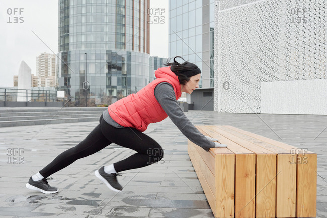 Young Caucasian Female Athlete Warming Up On Wooden Bench While