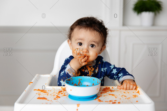 Toddler making a mess with a bowl of pasta sauce