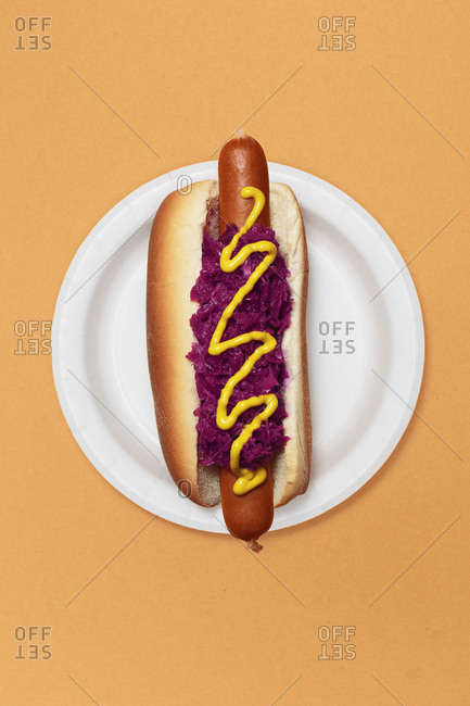 High Angle View of Hotdog with Purple Sauerkraut and Mustard on Roll Against Orange Background