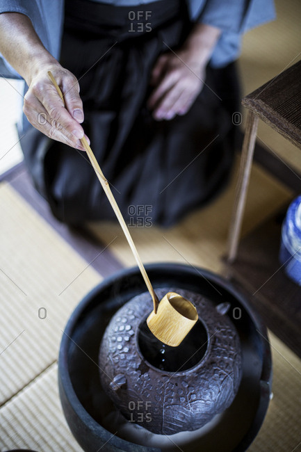 High angle close up of traditional Japanese Tea Ceremony, man using a Hishaku, a bamboo ladle, to pour hot water.