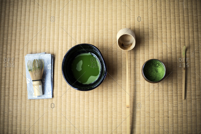 Tea ceremony utensils including bowl of green Matcha tea and bamboo whisk.