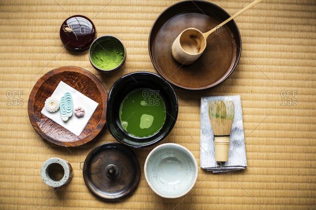 Tea ceremony utensils including bowl of green Matcha tea, a bamboo whisk and Wagashi sweets.