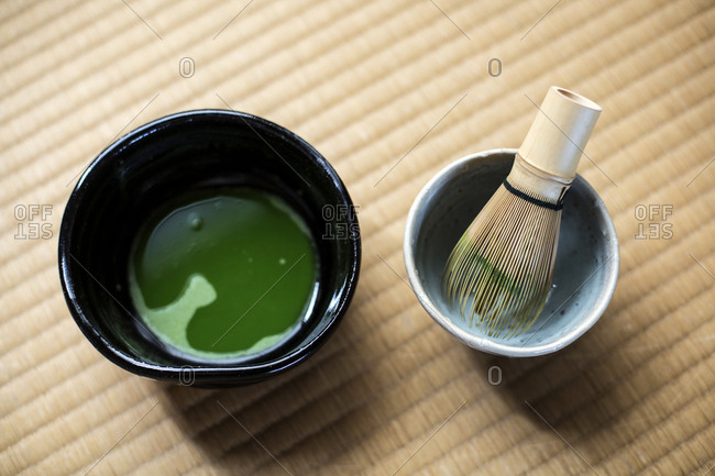 Tea ceremony utensils including bowl of green Matcha tea and bamboo whisk.