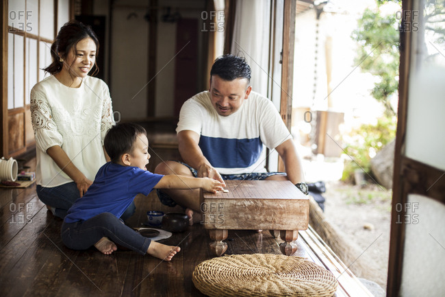 Japanese woman, man and little boy sitting on floor on porch of traditional Japanese house, playing Go.