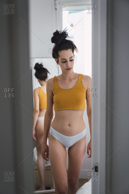Young woman in underwear at home reflected in mirror stock photo - OFFSET
