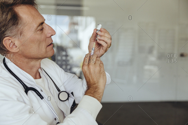 Doctor preparing injection- filling syringe