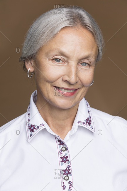 Portrait of smiling senior woman with grey hair wearing embroidered blouse