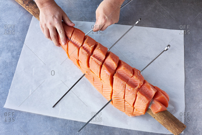 King salmon filet cut into portions and being prepared to be cooked on a pole outdoors.