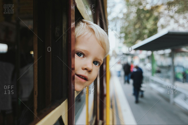 Young blonde boy looks out of tram window as it's travelling through the city of Melbourne Australia.