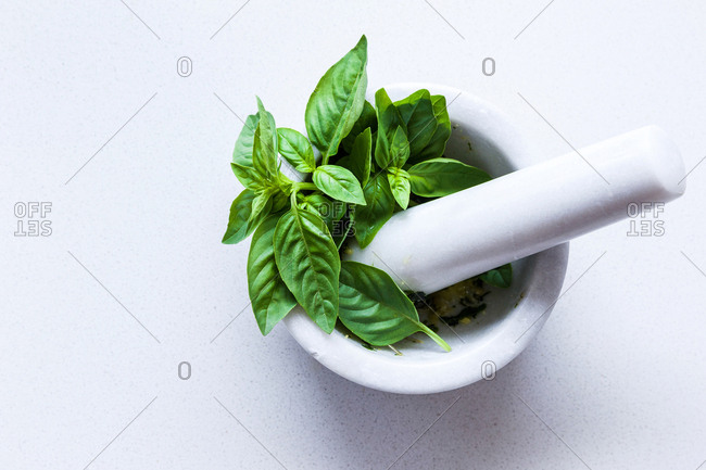 Fresh basil being made into pesto with mortar and pestle