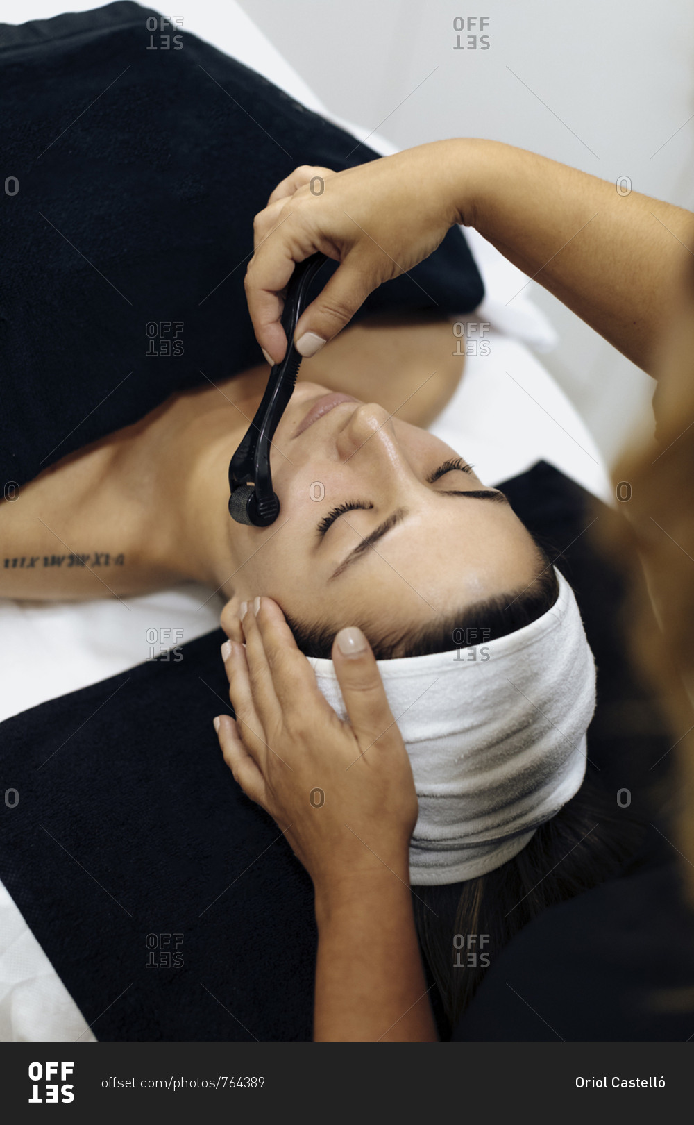 Aesthetician performing microneedling on woman's face during spa session