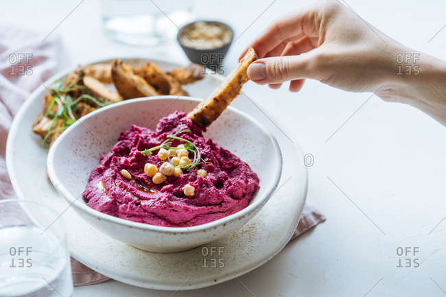 Woman dipping bread into beet dip
