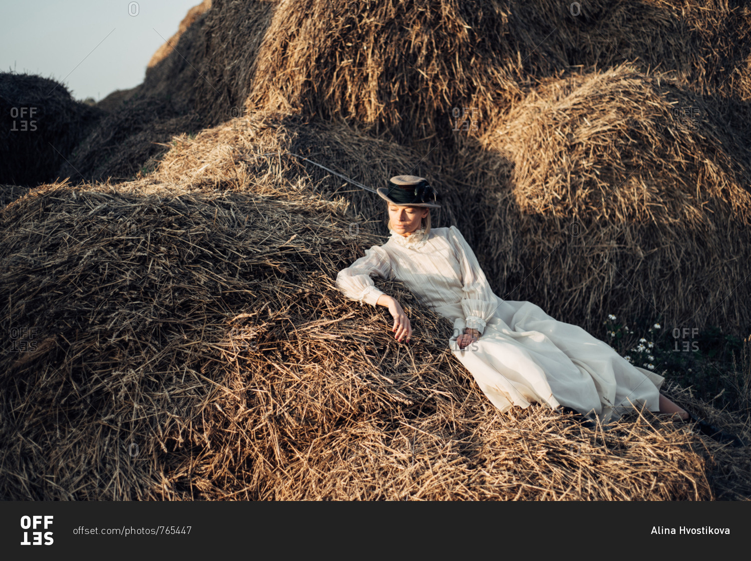 Woman dressed in vintage dress lying in a pile of hay