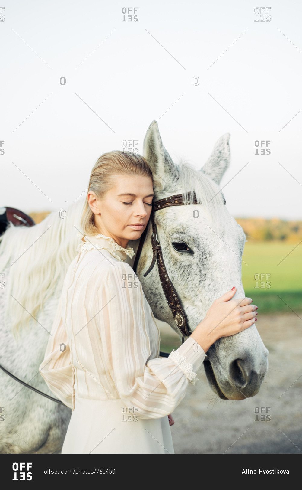 Woman dressed in vintage dress standing close with her horse