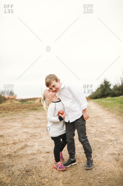 Little girl holding apple and giving her brother a kiss