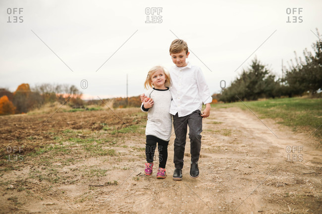 Two blonde siblings walking with arms around each other