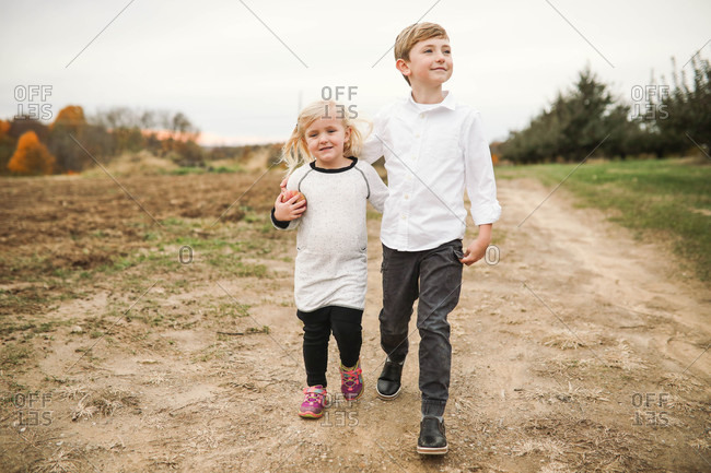 Two siblings walking with arms around each other