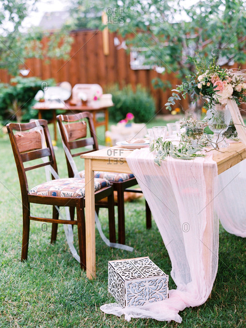 Wooden Table With Sheer Fabric Draped At An Outdoor Wedding Stock