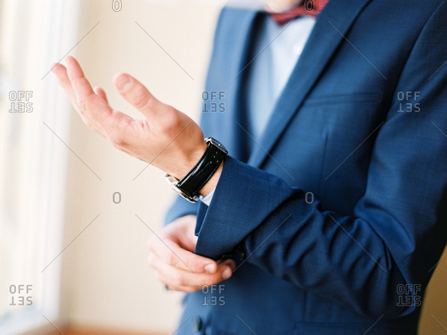 Groom buttoning his tuxedo jacket sleeve