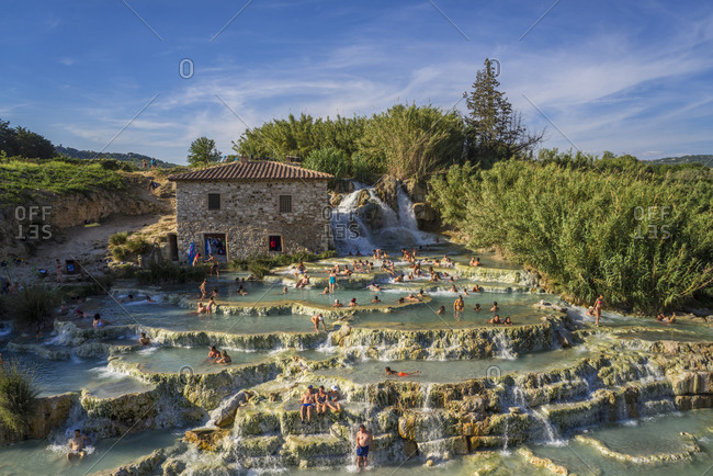 Italy, Tuscany - June 9, 2017: Saturnia, Cascate del Mulino. People lounging in sulfureous water that has renowned therapeutic properties, with limestone basins below