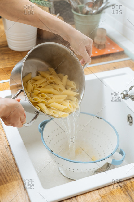 Woman draining noodles in sink
