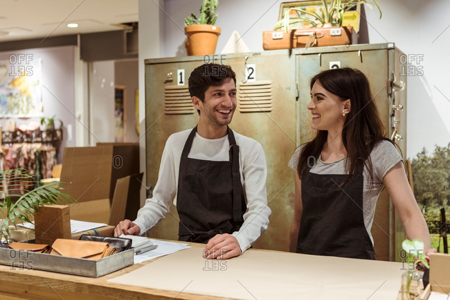Smiling male and female coworkers standing at checkout counter