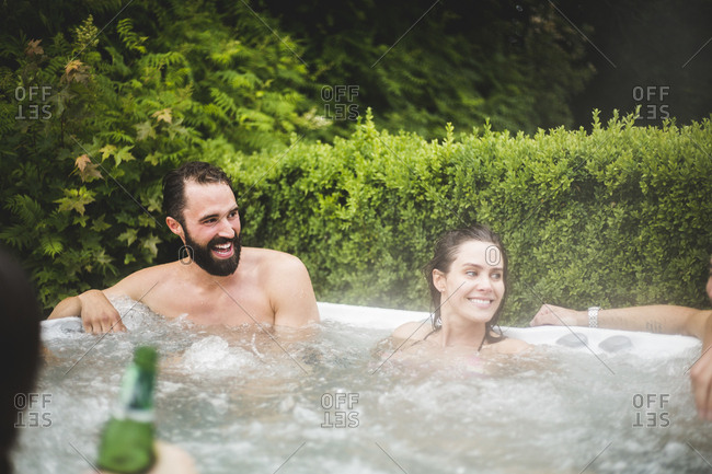 Cheerful male and female friends looking away while enjoying in hot tub
