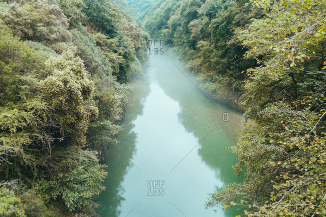 From above of blue water with haze above flowing slowly among shores with lush vegetation, Asturias