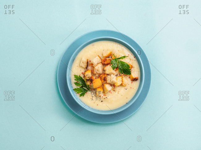 Cauliflower potato soup puree in blue bowl on blue minimalistic background. Top view flat lay. Copy space