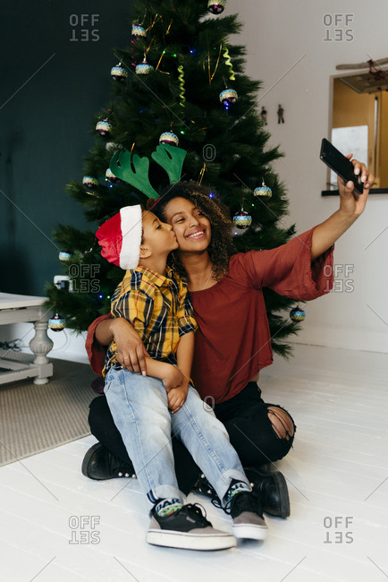 Funny black girl and kid disguised with Christmas accessories taking a self-portrait