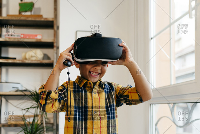 Cute black kid playing with VR glasses at home