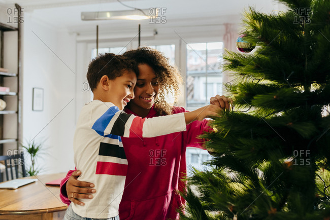 Young black woman with black kid placing balls on the Christmas tree