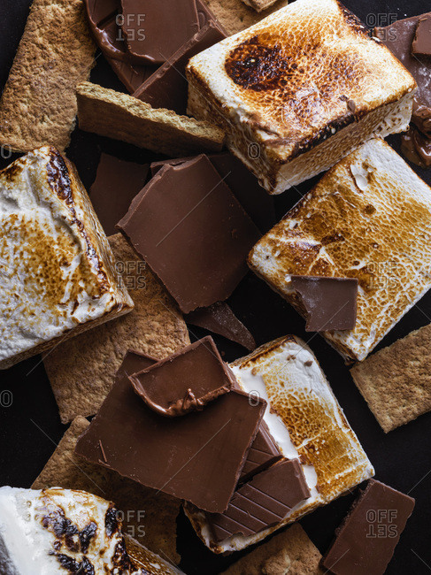 A messy pile of homemade, toasted marshmallows, graham cracker pieces and chocolate pieces.