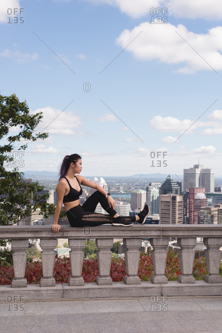 Female jogger relaxing on railing on a sunny day