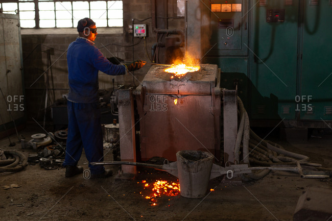 Male worker molting metal in foundry workshop
