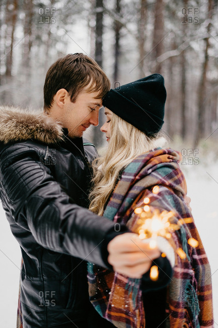 beautiful couple look at each other at christmas with sparklers