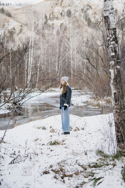 beautiful woman standing on freshly fallen snow. on the background of winter forest and river