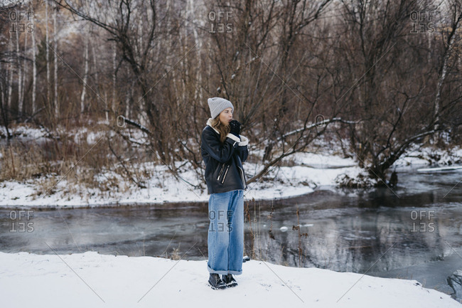 beautiful girl warm hands on the background of the winter forest and the river