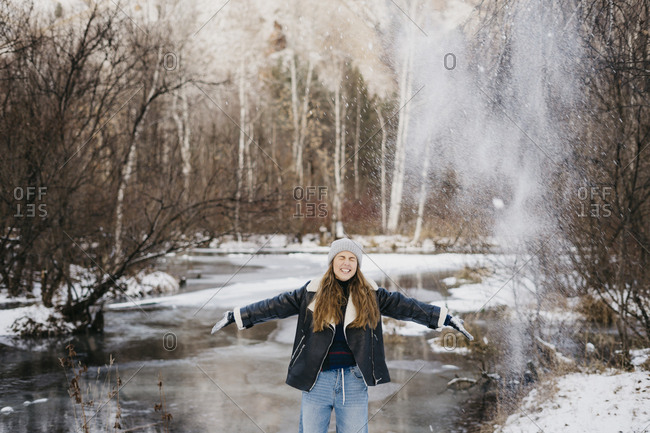 beautiful girl throws a snowball at a friend in the background of winter forest and river