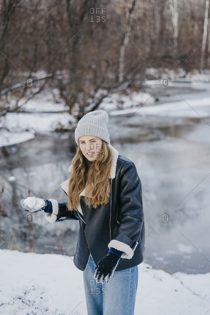 beautiful girl with a snowball in hand against the background of a winter river